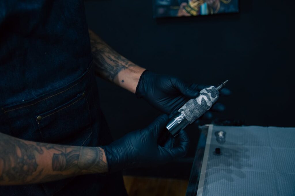 Close-up of a tattoo artist holding a tattoo machine, ready for inking session in a studio.